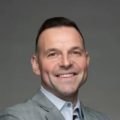 Jeffrey Getbehead smiling in a grey suit.